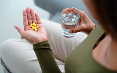 Девушка держит таблетки и стакан воды