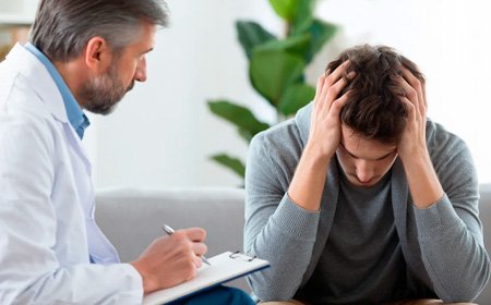 Мужчина сидит с врачом опустив голову в руки